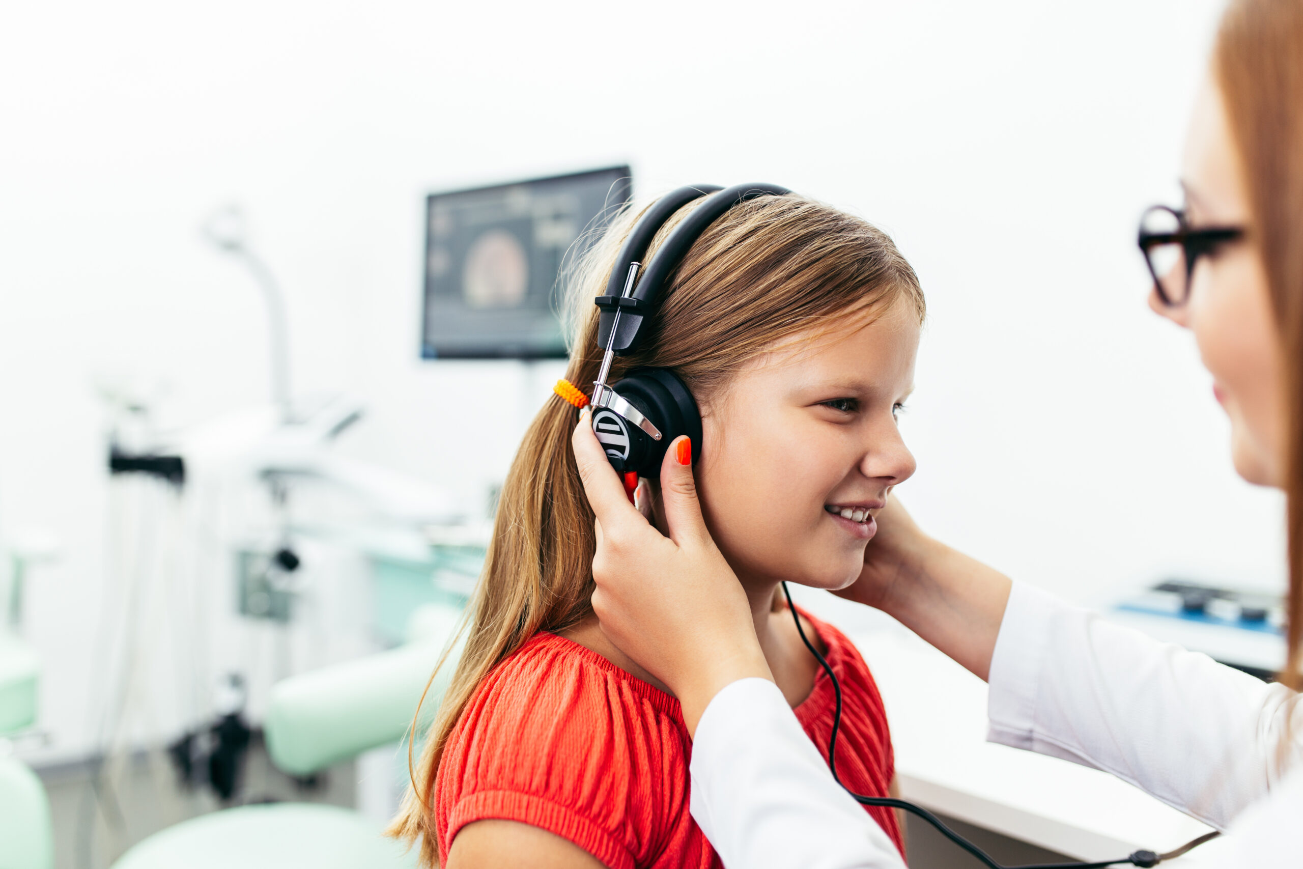 Young girl at medical examination or hearing aid checkup in otolaryngologist’s office